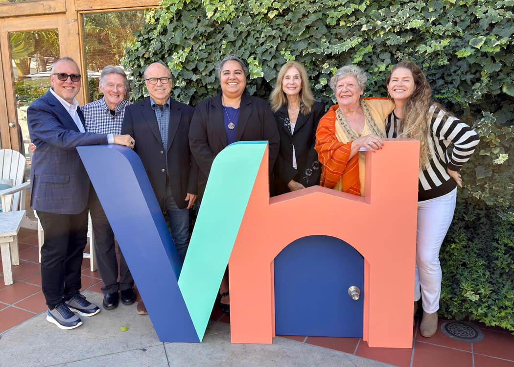 group smiling behind a Ventura Housing statue