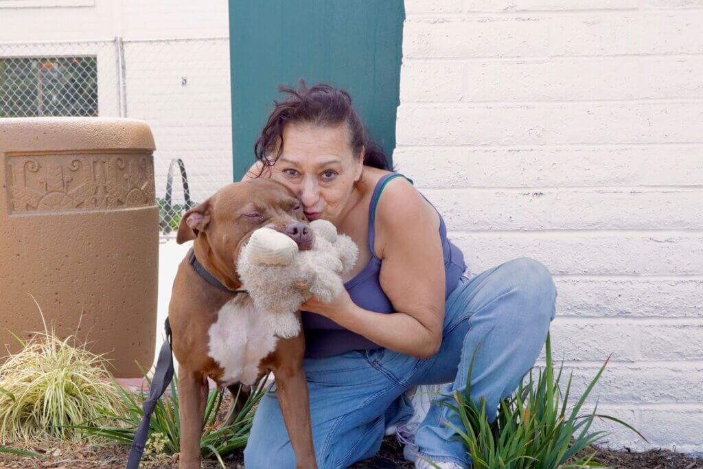 woman hugging dog with toy