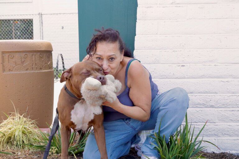 woman hugging dog with toy