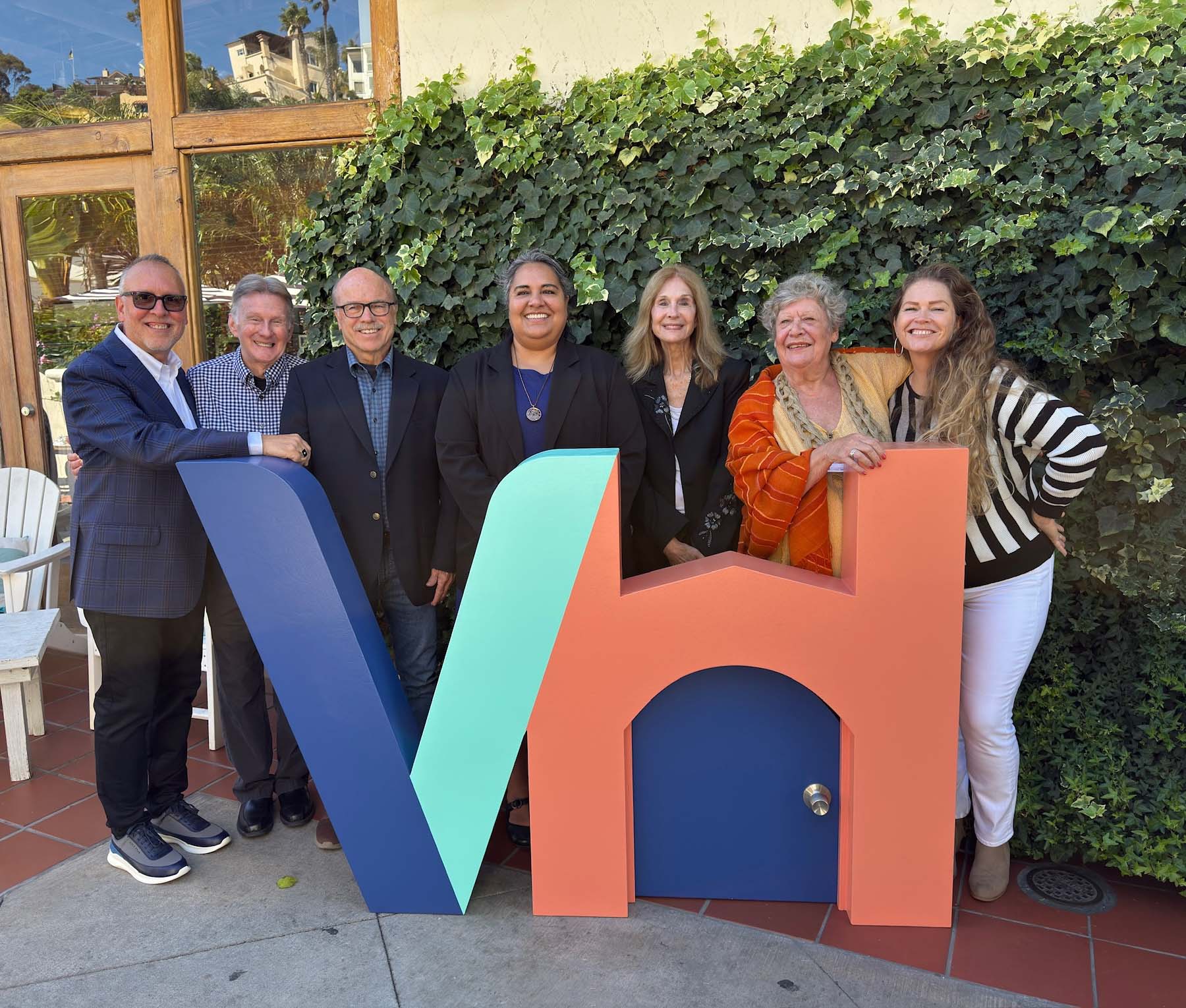 a group smiling by the VH sign