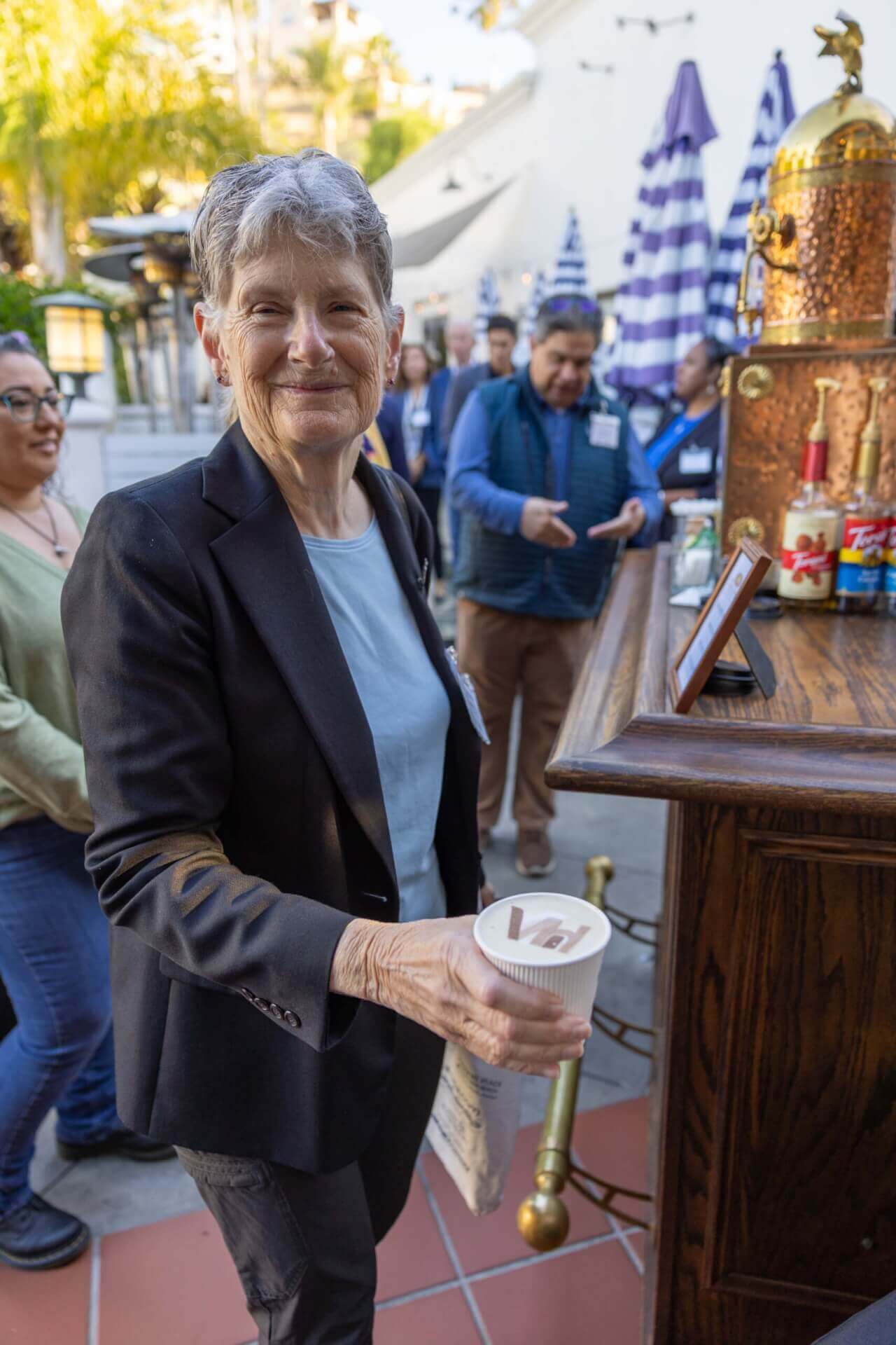 woman smiling with a coffee that has VH in the foam
