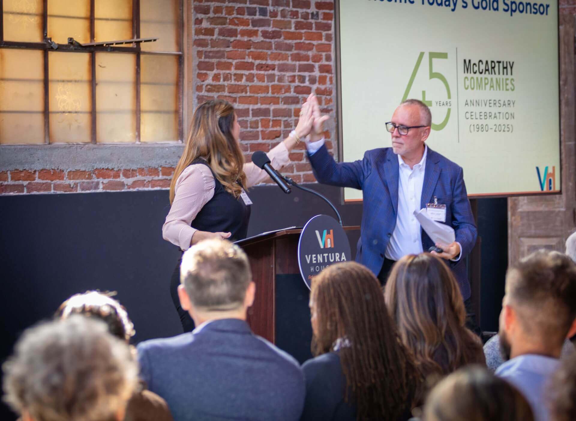 man and woman high fiving at a podium