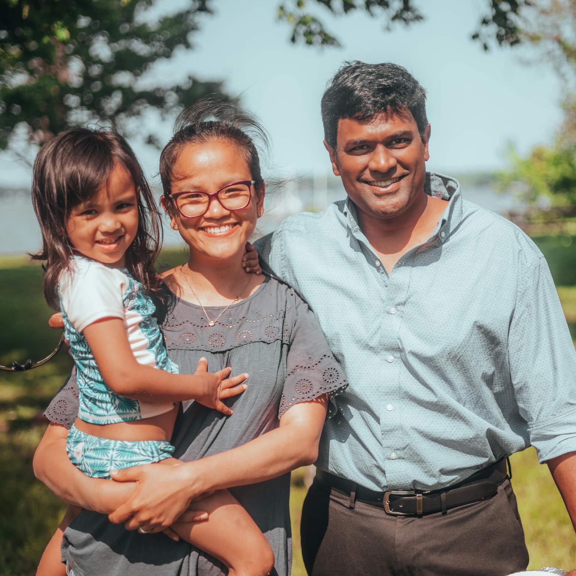 Smiling family enjoying time together outdoors in a sunny summer setting.